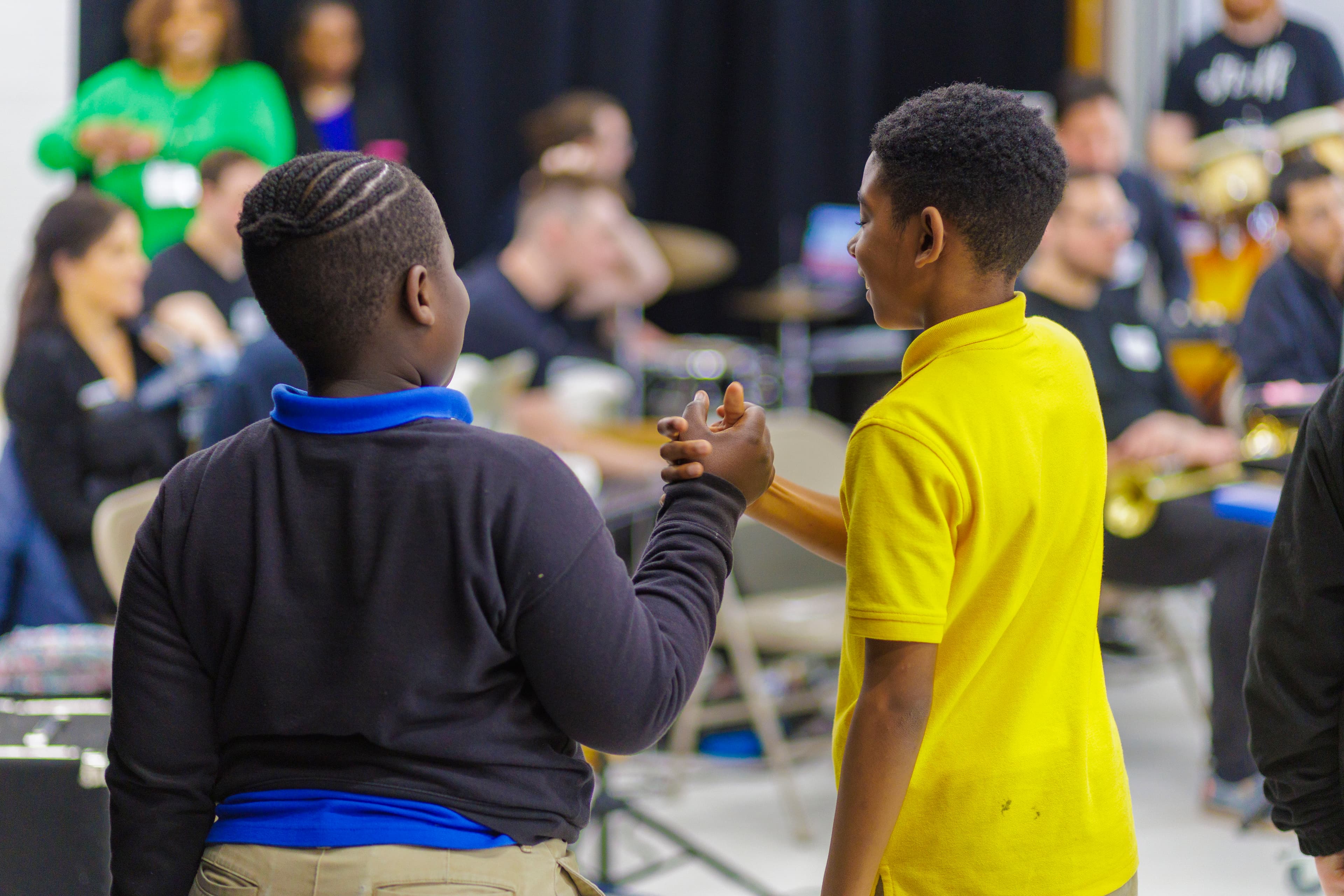 Two students high five in front of the band as their song begins