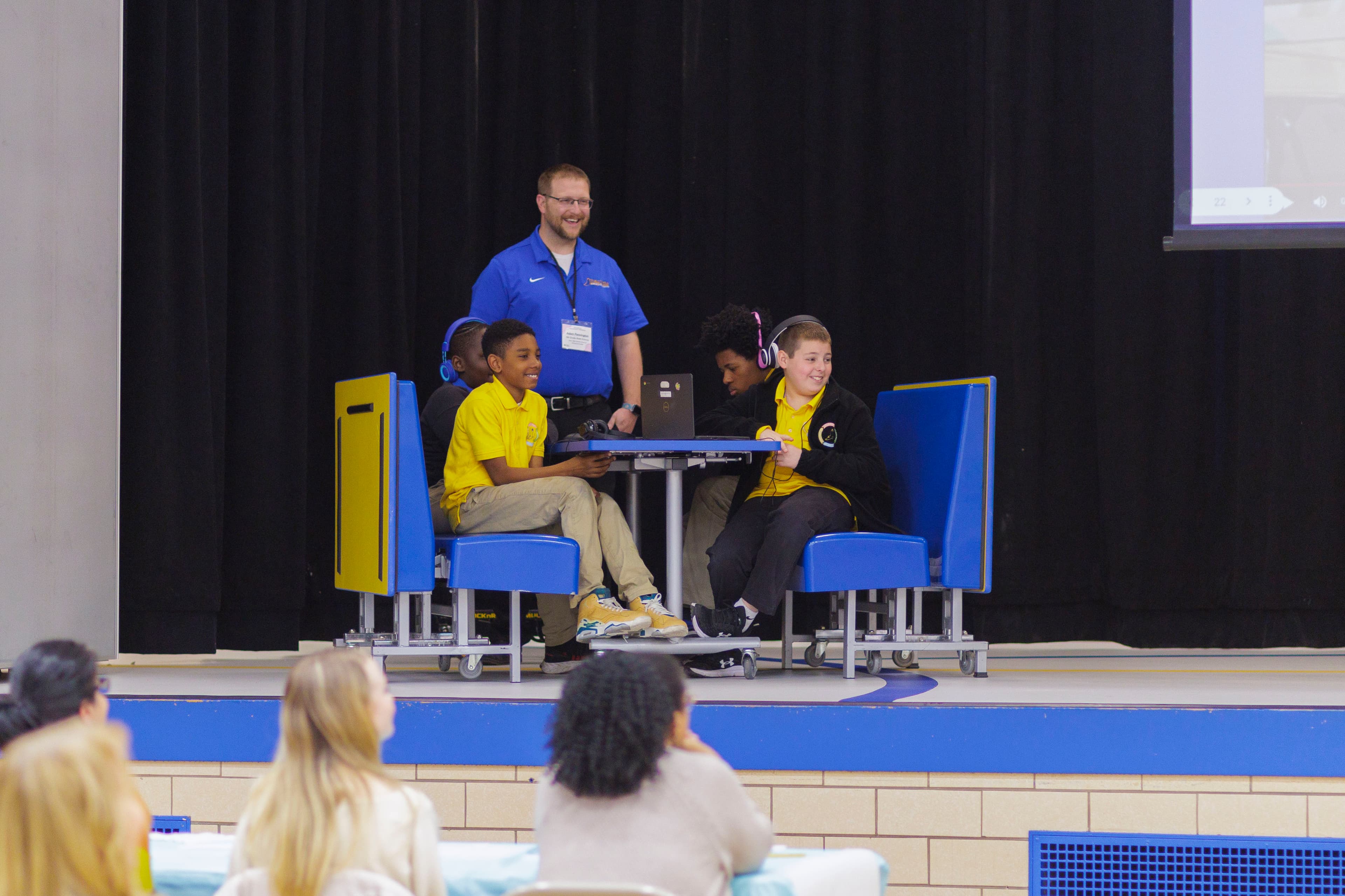 Students run their Conduction session from the stage while the school watches